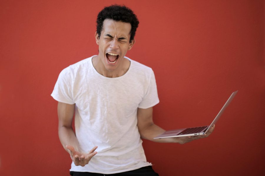 Stressed worker yelling while holding laptop